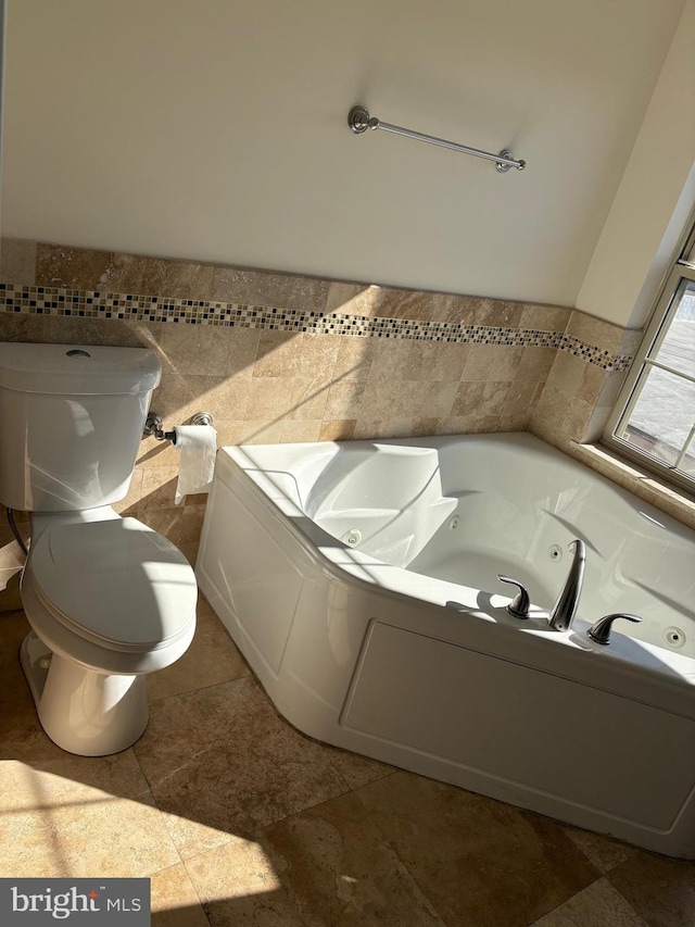 bathroom with a bathtub, toilet, and tile walls