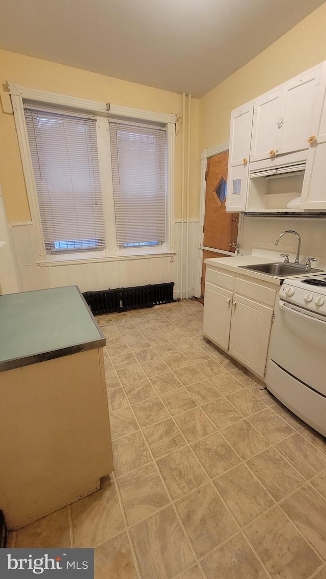 kitchen with white range oven, white cabinets, and sink