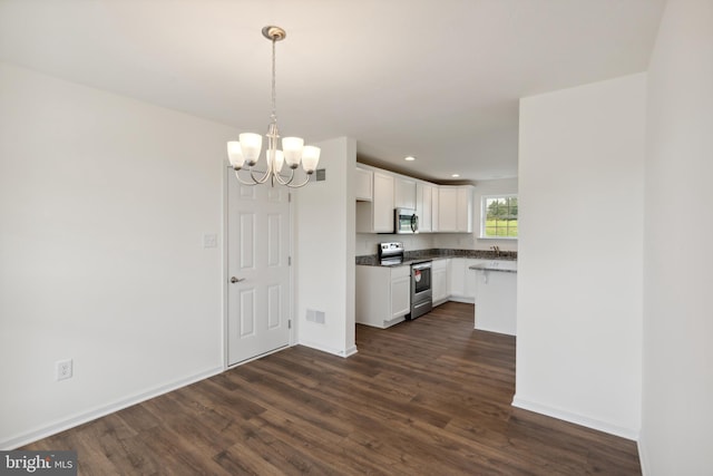 kitchen featuring appliances with stainless steel finishes, hanging light fixtures, white cabinetry, dark hardwood / wood-style flooring, and a notable chandelier