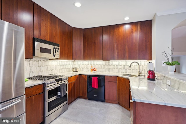 kitchen featuring sink, kitchen peninsula, decorative backsplash, appliances with stainless steel finishes, and light stone countertops