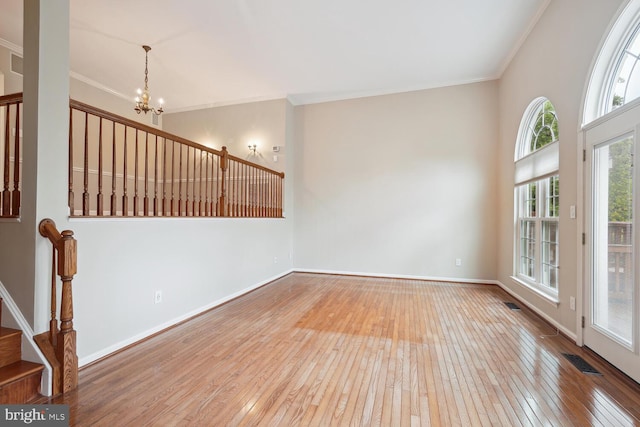 empty room with light hardwood / wood-style flooring, a chandelier, and ornamental molding