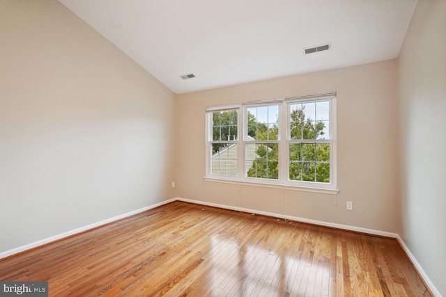 unfurnished room featuring light wood-type flooring and vaulted ceiling