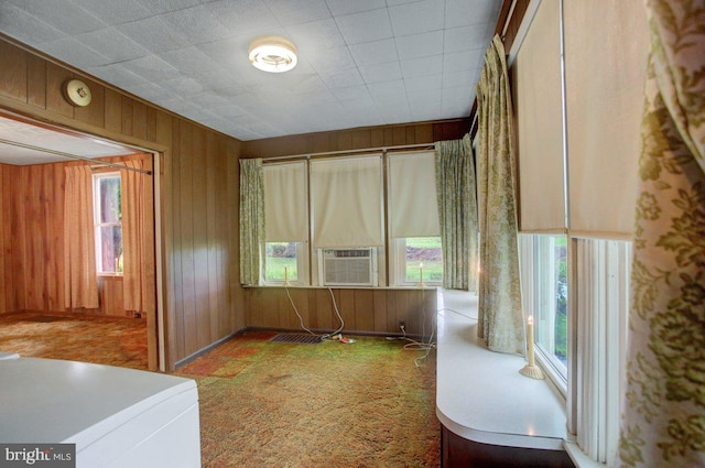 interior space featuring carpet, a wealth of natural light, wood walls, and cooling unit