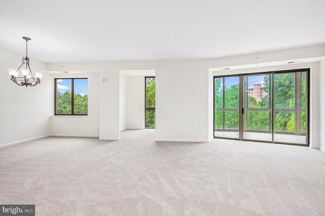 carpeted spare room with a notable chandelier