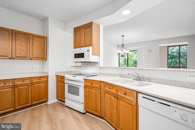 kitchen featuring light hardwood / wood-style floors, white appliances, pendant lighting, sink, and a notable chandelier