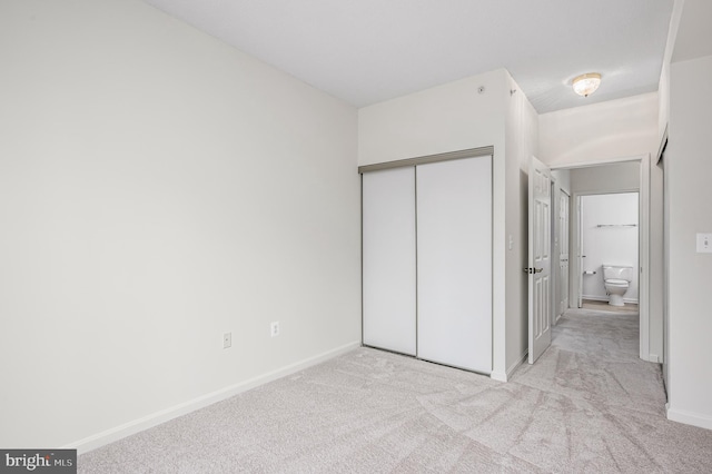 unfurnished bedroom featuring light carpet and a closet