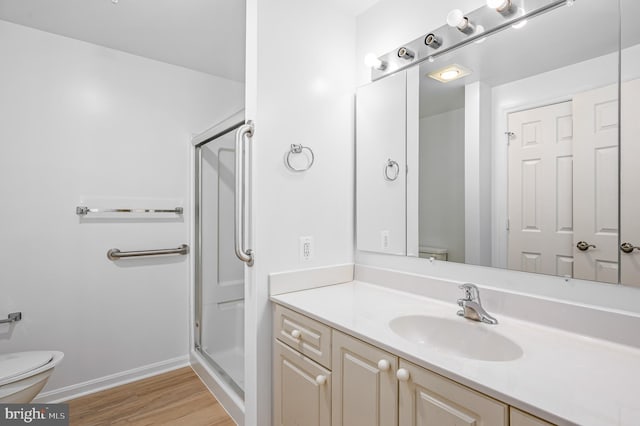 bathroom with wood-type flooring, vanity, toilet, and a shower with door