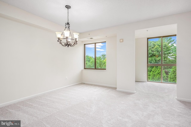 empty room featuring light carpet and a notable chandelier