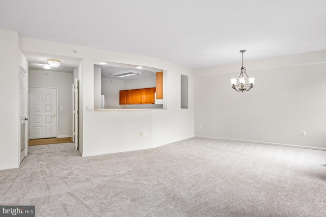 carpeted empty room featuring an inviting chandelier