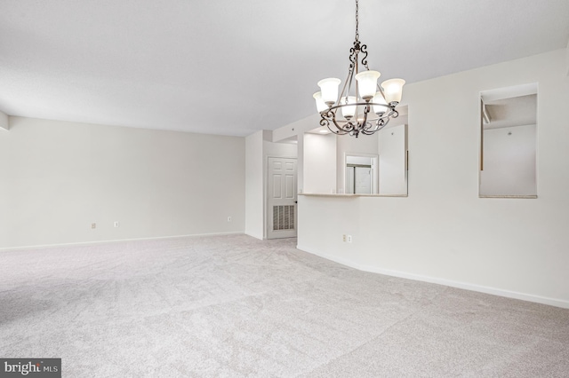 carpeted spare room featuring a chandelier