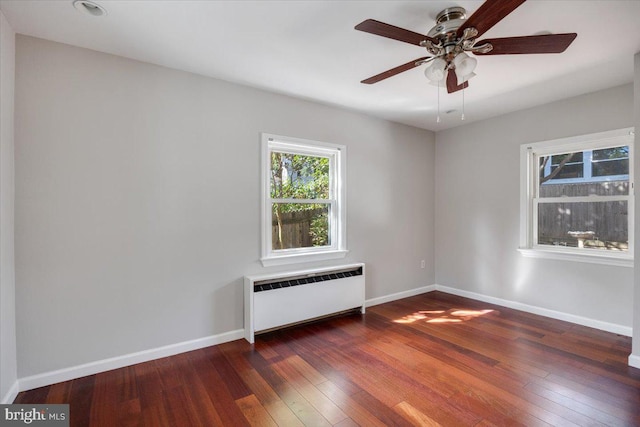 unfurnished room with ceiling fan, radiator heating unit, and dark hardwood / wood-style flooring