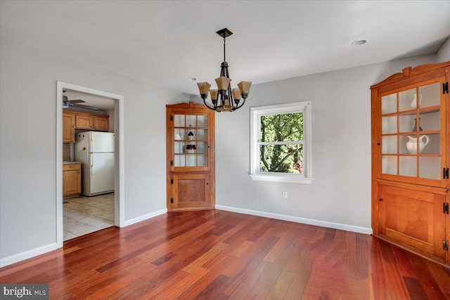 unfurnished dining area featuring a notable chandelier and light hardwood / wood-style flooring