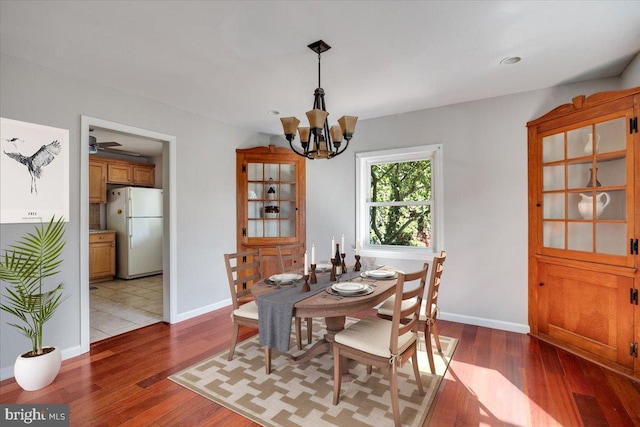 dining area featuring dark wood-type flooring and ceiling fan with notable chandelier