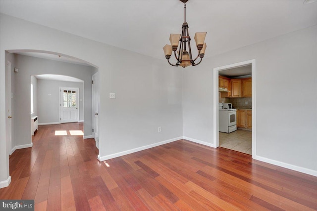 unfurnished room with a chandelier and light wood-type flooring