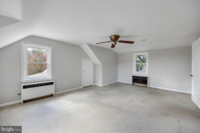 bonus room featuring lofted ceiling, light colored carpet, a healthy amount of sunlight, and radiator