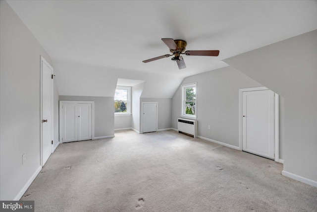 additional living space featuring light carpet, lofted ceiling, radiator heating unit, and ceiling fan