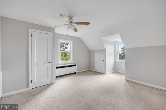 bonus room featuring radiator, vaulted ceiling, plenty of natural light, and light colored carpet