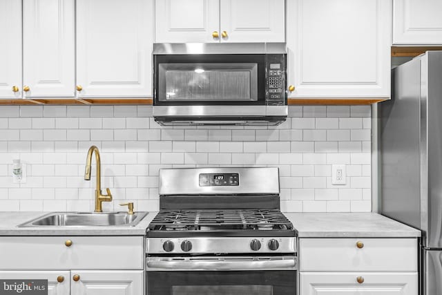 kitchen with stainless steel appliances, white cabinets, and tasteful backsplash