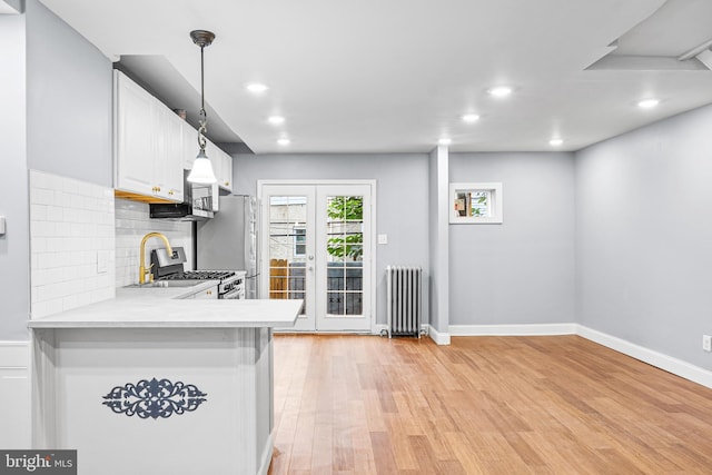 kitchen featuring radiator, white cabinets, pendant lighting, and kitchen peninsula