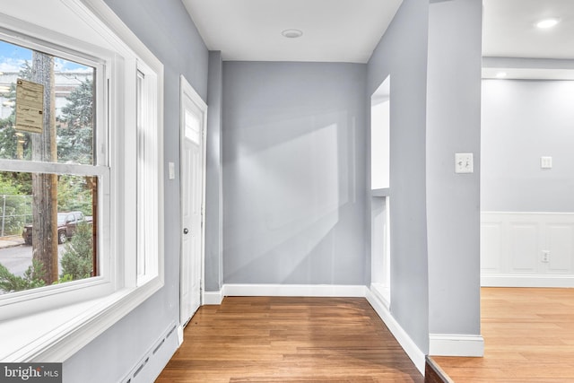 interior space with a baseboard radiator, light hardwood / wood-style floors, and a healthy amount of sunlight