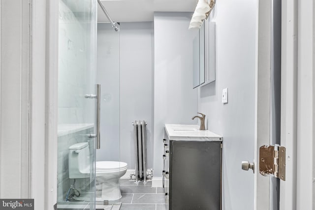 bathroom with a shower with shower door, vanity, radiator heating unit, tile patterned flooring, and toilet