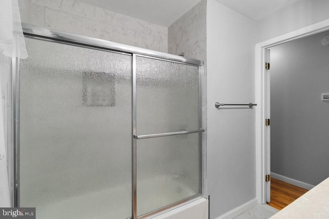 bathroom featuring shower / bath combination with glass door and hardwood / wood-style floors