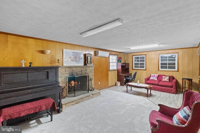 living room featuring a wall mounted air conditioner, a fireplace, a textured ceiling, wooden walls, and light colored carpet