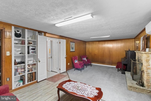 living area with a textured ceiling, a fireplace, wood walls, and light carpet