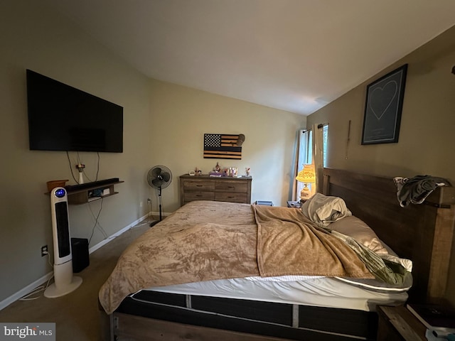 bedroom with dark colored carpet and lofted ceiling