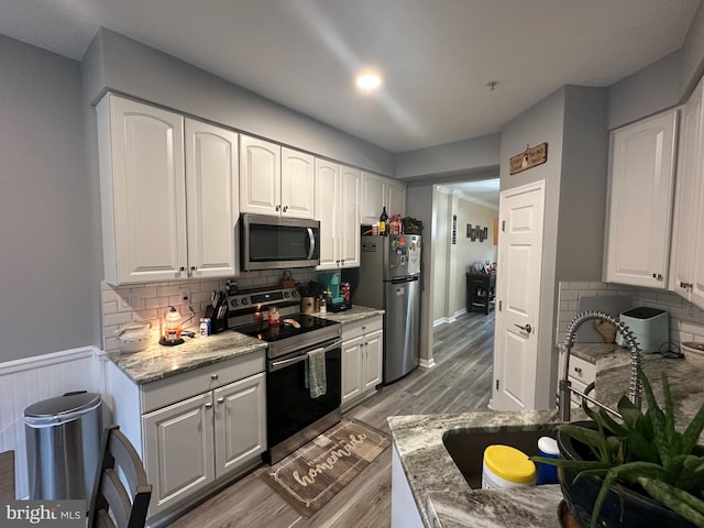 kitchen featuring white cabinets, sink, hardwood / wood-style flooring, appliances with stainless steel finishes, and light stone counters