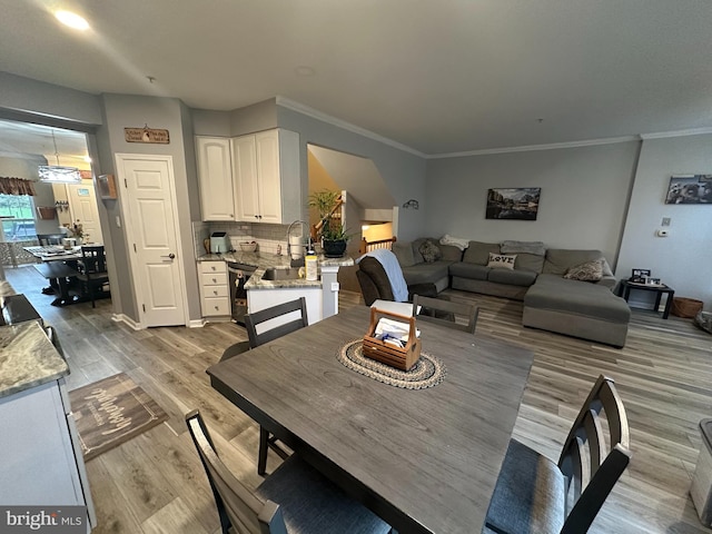 dining room featuring crown molding, light hardwood / wood-style flooring, and sink