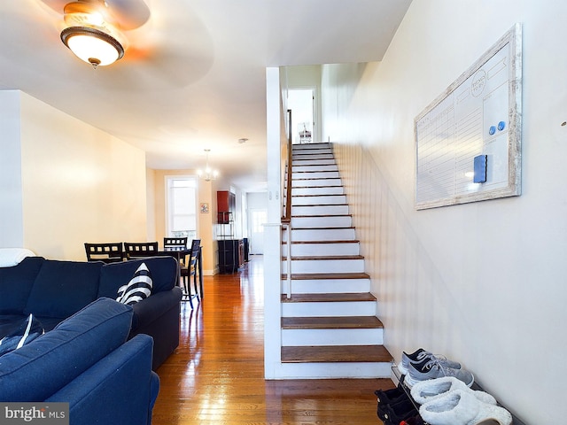 stairway with hardwood / wood-style floors and a notable chandelier