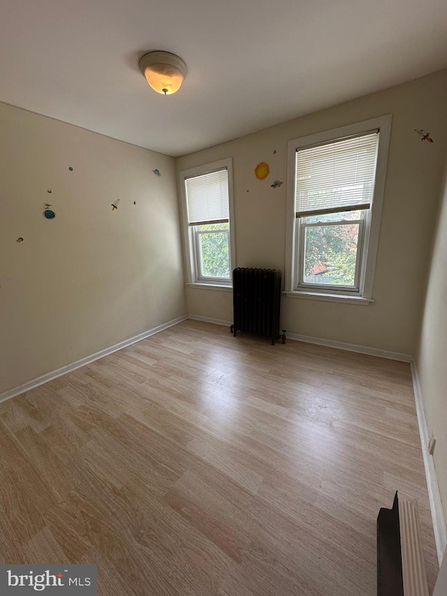 unfurnished room featuring radiator and light hardwood / wood-style floors