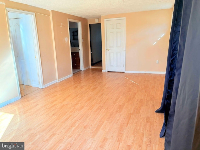 empty room with light hardwood / wood-style flooring and a textured ceiling