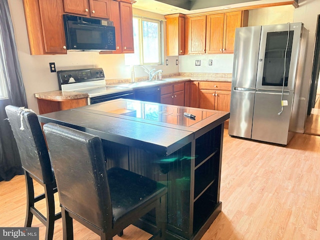 kitchen featuring electric range, light hardwood / wood-style flooring, stainless steel refrigerator, and sink