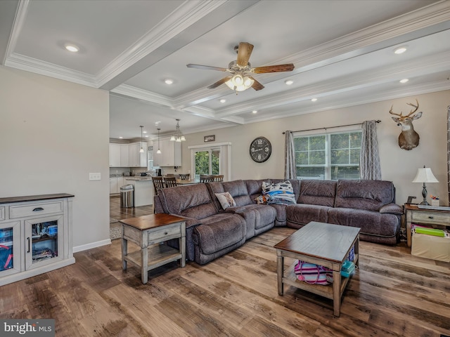 living room featuring ornamental molding, light wood-type flooring, beam ceiling, and ceiling fan