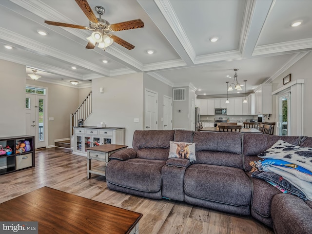 living room with ceiling fan with notable chandelier, beam ceiling, light hardwood / wood-style floors, and ornamental molding