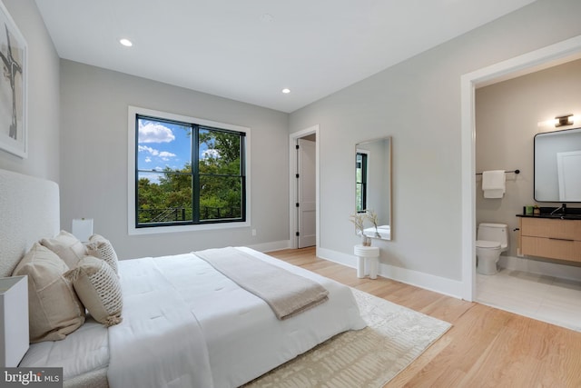 bedroom featuring connected bathroom and light hardwood / wood-style floors