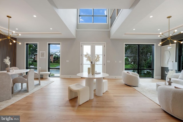 living room with a raised ceiling, light hardwood / wood-style floors, and an inviting chandelier