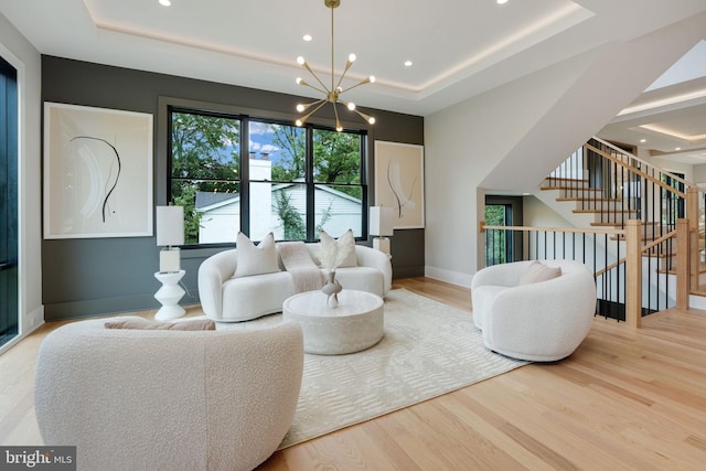 living room with a tray ceiling, a chandelier, and hardwood / wood-style floors