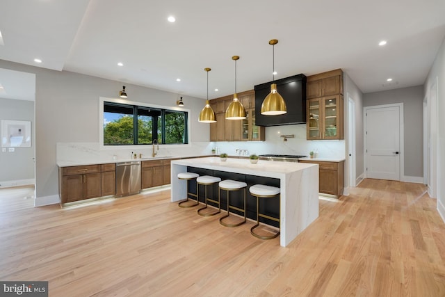 kitchen featuring dishwasher, light hardwood / wood-style floors, a breakfast bar area, and decorative light fixtures