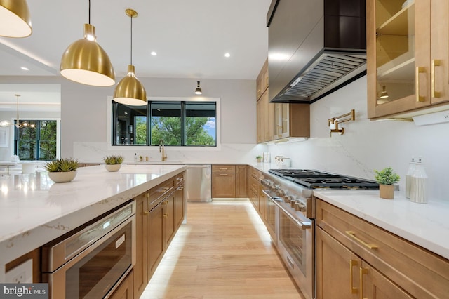 kitchen featuring appliances with stainless steel finishes, wall chimney exhaust hood, light stone countertops, and a wealth of natural light