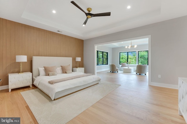 bedroom with ceiling fan with notable chandelier and light hardwood / wood-style floors