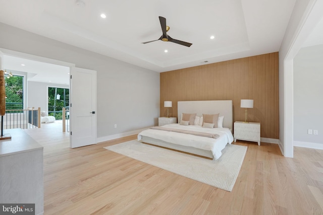 bedroom featuring ceiling fan, light wood-type flooring, a raised ceiling, and access to outside