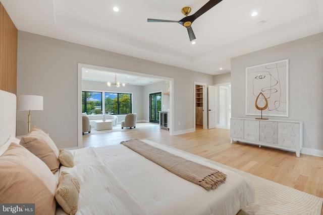 bedroom featuring ceiling fan with notable chandelier, light hardwood / wood-style floors, a walk in closet, and a closet