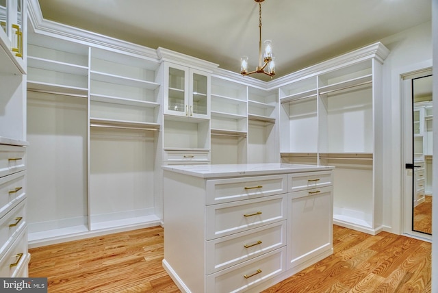 spacious closet featuring light hardwood / wood-style flooring and a chandelier