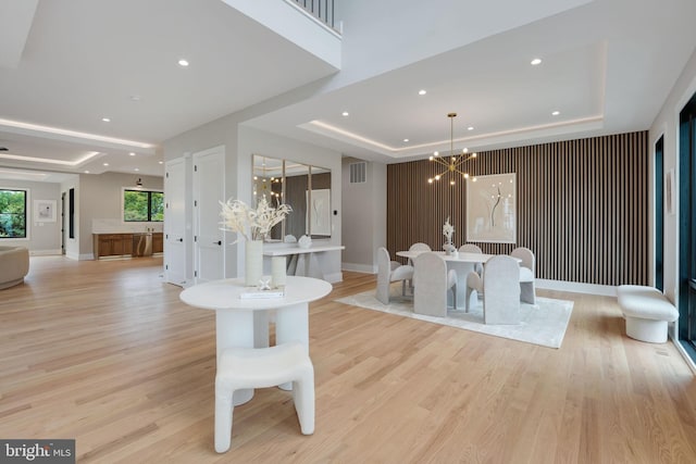 living room with light hardwood / wood-style flooring, a tray ceiling, and a chandelier