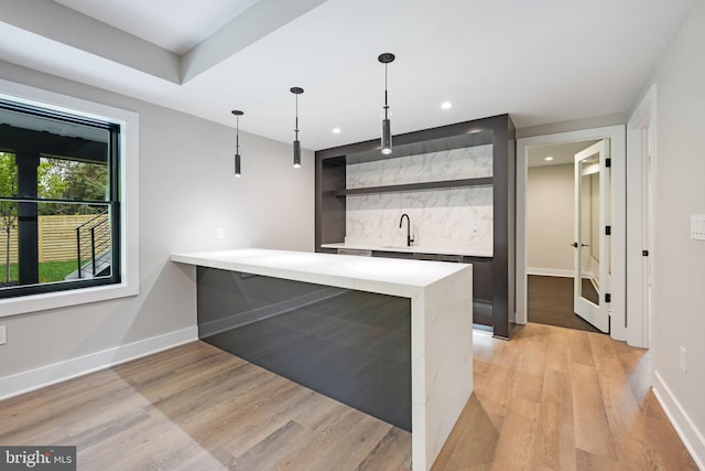 kitchen with pendant lighting, kitchen peninsula, light hardwood / wood-style flooring, and sink