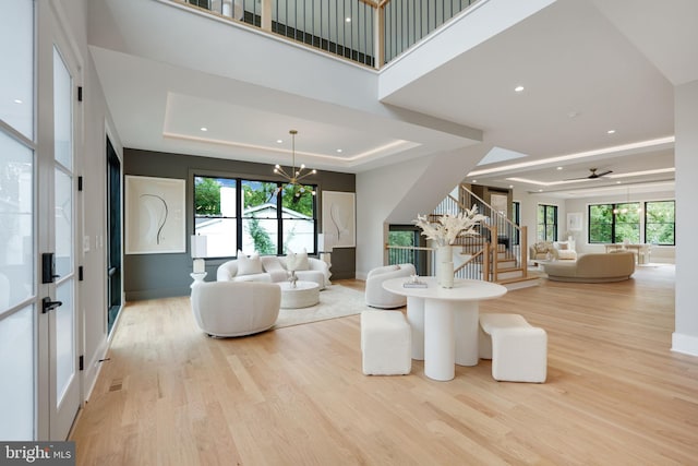 living room with light wood-type flooring, plenty of natural light, and a tray ceiling