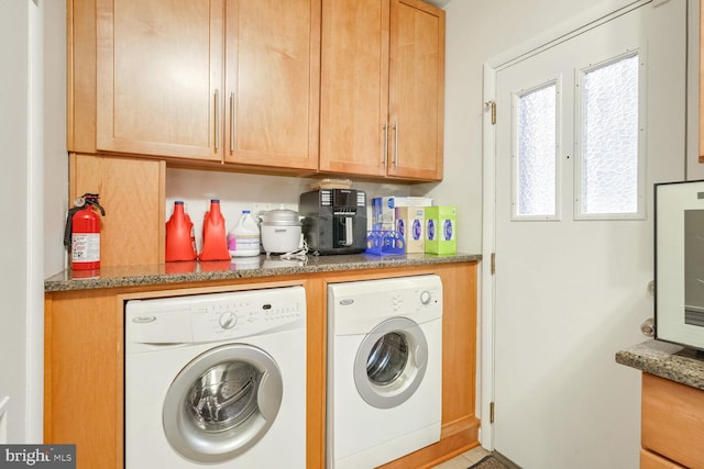 clothes washing area featuring cabinets and separate washer and dryer